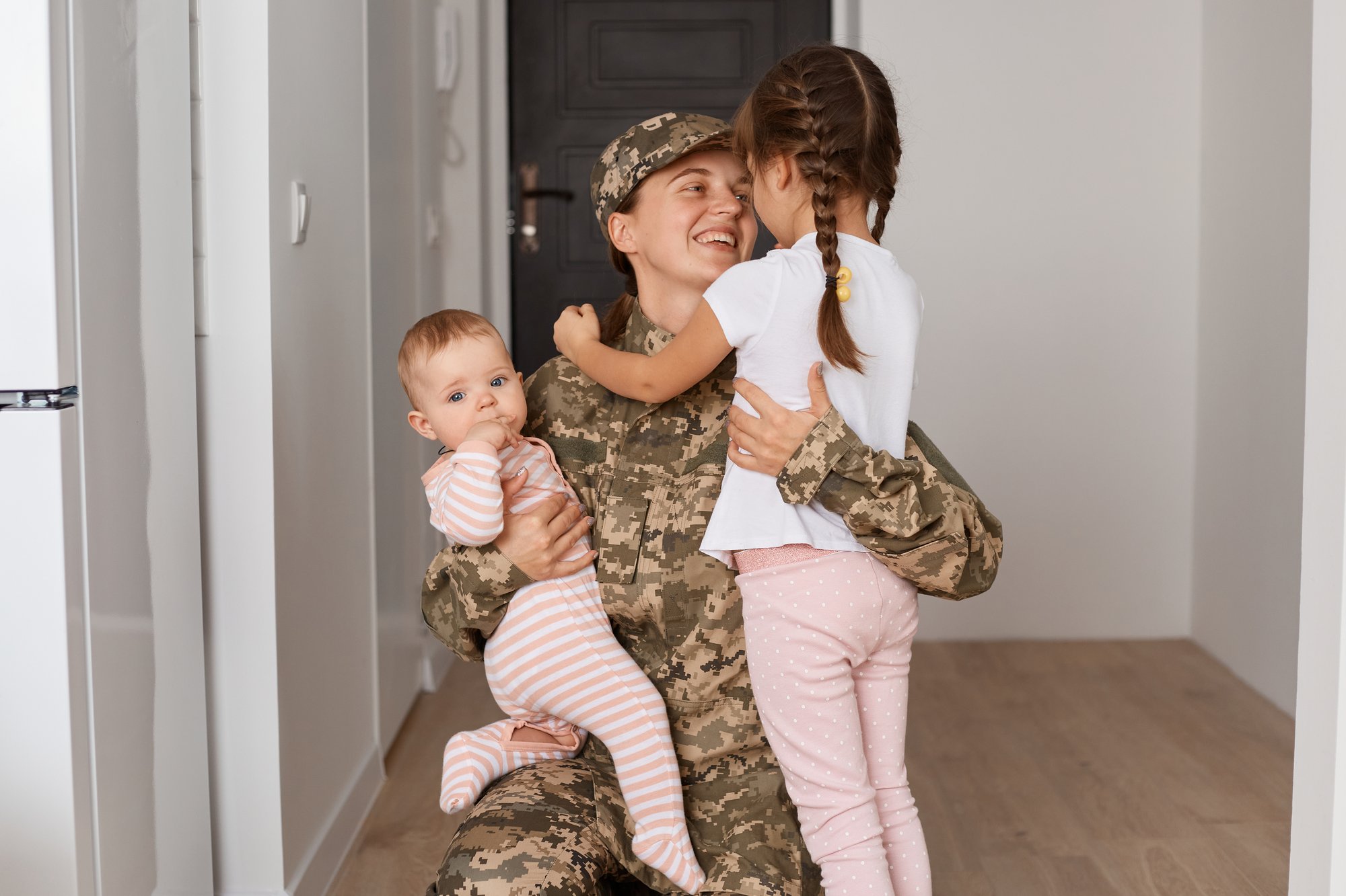 military woman hold two young kids